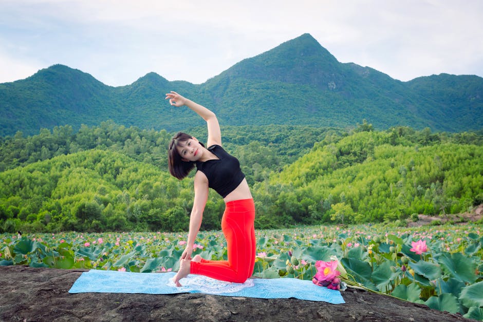 Woman practicing yoga amidst vibrant lotus fields with mountains in Hội An.