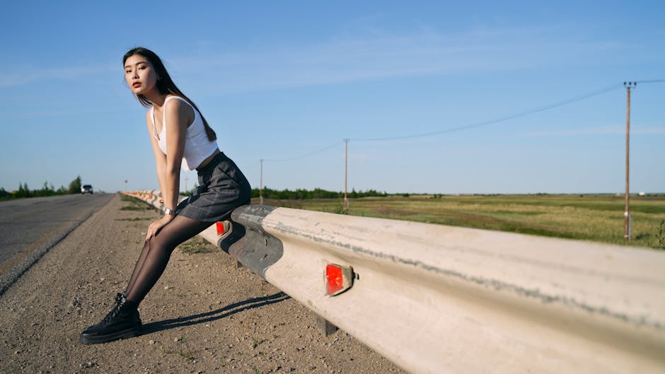 Fashionable woman posing outdoors by a road, capturing a modern and stylish vibe.